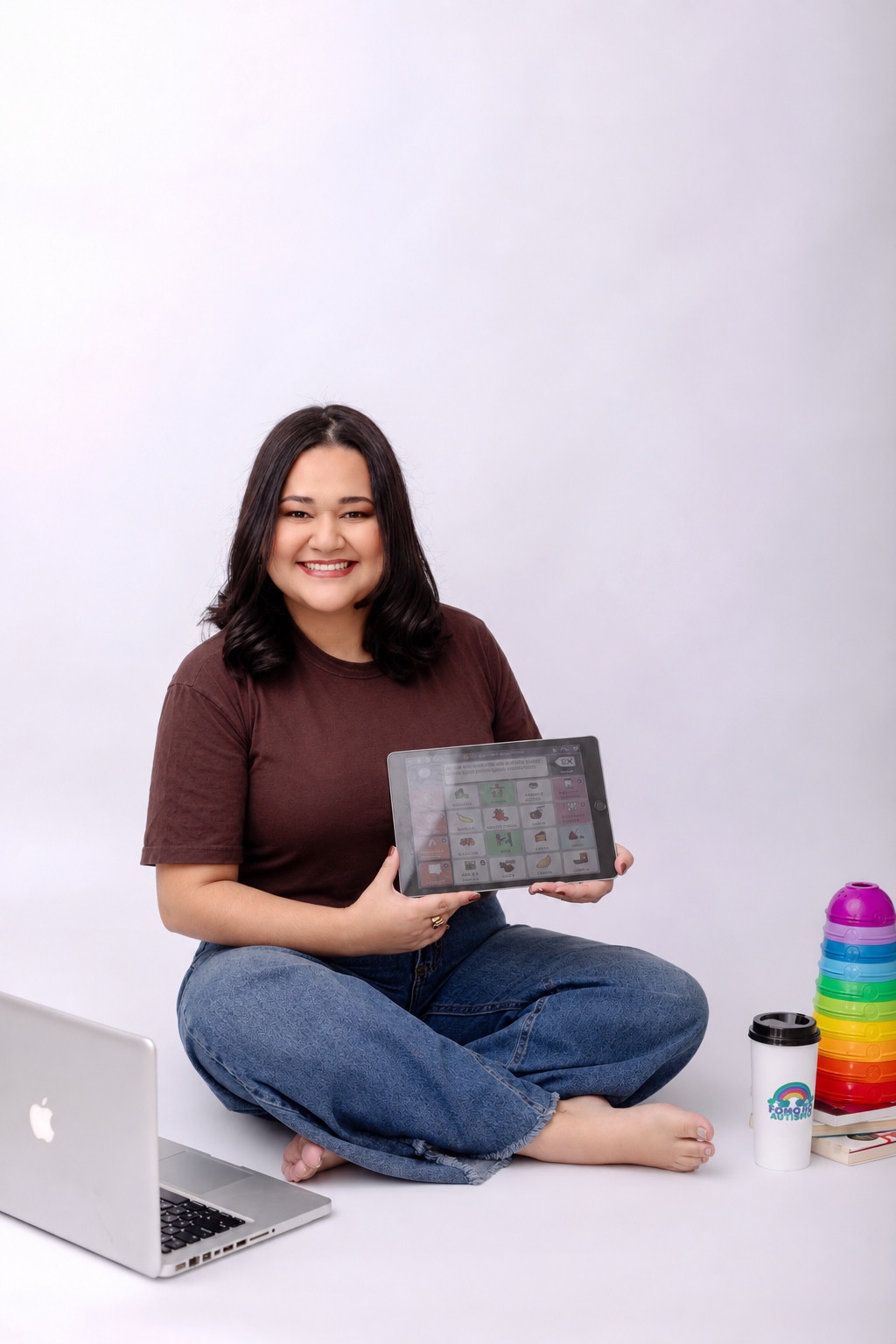 Bia Falcão sorrindo e segurando um tablet com um recurso de Comunicação Aumentativa e Alternativa.